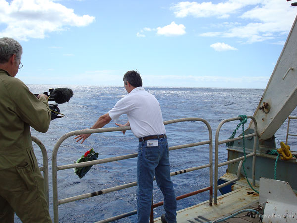 David Mearns casting a floral wreath into the sea from the back of the ship.