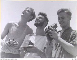 ABOARD HMAS SYDNEY TAKING PHOTOGRAPHS OF THE EFFECTS OF BATTLE WITH THEIR CAMERAS, STOKERS J. HARD AND J.H. HEASLEWOOD AND ABLE SEAMAN A.J. CLARK.