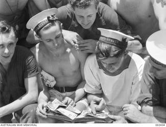 HMAS SYDNEY CREW MEMBERS LOOK AT PHOTOGRAPHS, PRECIOUS RECORDS OF THE SHIP'S ACTIVITIES.