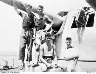 Informal portrait of four members of the crew of HMAS Sydney in front of one of the ship's gun mounts: Able Seaman (AB) PA1679 Douglas James Burrowes (back row, right) of Stepney, SA; 22831 Able Seaman (AB) Robert Underdown Ewens, (front row, left), of Millswood, SA; and two unidentified sailors. AB Burrowes enlisted on 29 November 1939, and joined the crew of HMAS Sydney on 30 January 1940. AB Ewens enlisted in the Navy on 6 February 1939, and joined the crew of HMAS Sydney on 18 April 1940. Both men were killed in action on 20 November 1941, when HMAS Sydney sank with the loss of all its crew, following the battle with the German raider Kormoran.