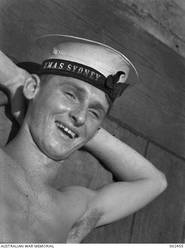 Aboard HMAS SYDNEY, a Rating F2803/21 AB Thomas Patrick Fisher RAN relaxes after lunch. Fisher was born in Geraldton, WA, and his home port was Fremantle, WA.