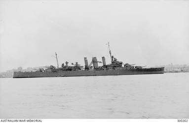SYDNEY, NSW. 1943. STARBOARD BROADSIDE VIEW OF THE HEAVY CRUISER HMAS AUSTRALIA (II) AT ANCHOR. THE EXTREMELY DARK GREY COLOUR SCHEME WHICH SHE WORE EARLIER IN THE YEAR HAS EITHER FADED OR BEEN REPLACED BY A SOMEWHAT LIGHTER SHADE, EITHER MS2 OR THE NEWER G10 WHICH WAS INTRODUCED THAT YEAR. SHE IS FITTED WITH TYPE 271 SURFACE SEARCH RADAR IN ITS DISTINCTIVE LANTERN MOUNTED IMMEDIATELY ABAFT THE DIRECTOR. TYPE 284 FIRE CONTROL RADAR FOR THE MAIN ARMAMENT IS FITTED TO THE FACE OF THE DIRECTOR. AMERICAN SC RADAR IS FITTED AT THE TOP OF HER FOREMAST FROM WHICH FLIES THE FLAG OF THE REAR ADMIRAL COMMANDING THE AUSTRALIAN SQUADRON. HER MAINTOPMAST HAS BEEN STRUCK. THE CLOSE RANGE ANTI AIRCRAFT ARMAMENT HAS BEEN AUGMENTED BY THE ADDITION OF TEN 20MM OERLIKON AA GUNS. TWO ARE MOUNTED IN TUBS ON EACH OF B AND X TURRETS, FOUR ARE MOUNTED PORT AND STARBOARD AMIDSHIPS AND THE REMAINING TWO ARE IN TUBS AT THE BASE OF THE SEARCHLIGHT TOWER. ON THE CATAPULT IS AIRCRAFT D OF NO 9 SQUADRON, RAAF, A SUPERMARINE WALRUS AMPHIBIAN AIRCRAFT (OR SEAGULL V). (NAVAL HISTORICAL COLLECTION).