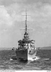 OFF SYDNEY, NSW. 1939-10-20. HEAD ON VIEW OF THE HEAVY CRUISER HMAS AUSTRALIA (II) AS SHE APPEARED AFTER HER 1938-1939 REFIT. THE SHIP HAS HAD HER BRIDGEWORK EXTENDED. THE FOUR SINGLE 4 INCH MK V AA GUNS HAVE BEEN REPLACED BY EIGHT TWIN 4 INCH MK XVI WEAPONS ON MK XIX MOUNTINGS. S1 AND P1 MOUNTINGS CAN BE SEEN ON THE UPPER DECK BETWEEN THE BOATS AND THE SUPERSTRUCTURE. A NEW DIRECTOR CONTROL TOWER HAS BEEN FITTED AND THE ORIGINAL MOVED AFT, REPLACING THE HIGH ANGLE CONTROL POSITION AND THE ORIGINAL CRANE. NEW HIGH ANGLE CONTROL POSITIONS ARE PROMINENT IN THE BRIDGE WINGS. (NAVAL HISTORICAL COLLECTION).