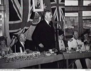 COCKATOO ISLAND DOCKYARD, SYDNEY, NSW. 1940-02-10. THE PRIME MINISTER, MR R. G. MENZIES, SPEAKING AT THE LUNCHEON AFTER THE LAUNCHING OF THE SLOOP HMAS WARREGO (II). THOSE SEATED ARE: MRS R. G. MENZIES, WIFE OF THE PRIME MINISTER AND LAUNCHING LADY; SIR GEORGE DAVIS KT, CHAIRMAN OF DIRECTORS, COCKATOO DOCK AND ENGINEERING COY PTY LTD; LADY DAVIS; ADMIRAL SIR RAGNAR COLVIN KBE CB RAN, FIRST NAVAL MEMBER; UNIDENTIFIED. (NAVAL HISTORICAL COLLECTION).