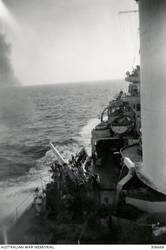 AEGEAN SEA. 1940-07-28. P.1 4 INCH MARK V AA GUN ON THE CRUISER HMAS SYDNEY (II) FIRING AT ITALIAN BOMBERS DURING AN ATTACK WHICH OCCURRED DURING THE OPERATION TO INTERCEPT AND SINK THE ITALIAN CONTROLLED GREEK TANKER ERMIONI CARRYING PETROL AND OIL TO ITALIAN NAVAL AND AIR BASES IN THE DODECANESE ISLANDS. THE QUADRUPLE .5 INCH AA MACHINE IN THE PORT BRIDGE WING IS VISIBLE JUST RIGHT OF CENTRE. (NAVAL HISTORICAL COLLECTION).