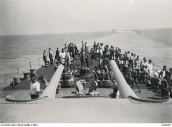 AEGEAN SEA. 1940-07-28. MEMBERS OF THE SHIP'S COMPANY OF THE CRUISER HMAS SYDNEY (II) ON THE FORECASTLE DURING THE OPERATION TO INTERCEPT AND SINK THE ITALIAN CONTROLLED GREEK TANKER ERMIONI. THE CRUISER HMS NEPTUNE IS IN THE DISTANCE. (NAVAL HISTORICAL COLLECTION).