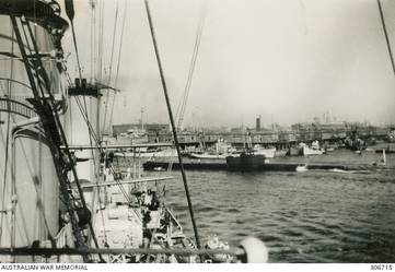ALEXANDRIA, EGYPT. 1940-07-31. PORT SIDE VIEW OF THE SUBMARINE HMS RAINBOW PASSING HMAS SYDNEY (II). IN THE BACKGROUND ARE ARMED TRAWLERS OF THE ROYAL NAVY AND THE REPAIR SHIP HMS RESOURCE. (NAVAL HISTORICAL COLLECTION).