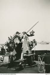 ALEXANDRIA, EGYPT. 1940-09-05. P.2 4 MARK V INCH AA GUN OF THE CRUISER HMAS SYDNEY (II). IN THE RIGHT BACKGROUND IS THE HOSPITAL SHIP MAINE. (NAVAL HISTORICAL COLLECTION).