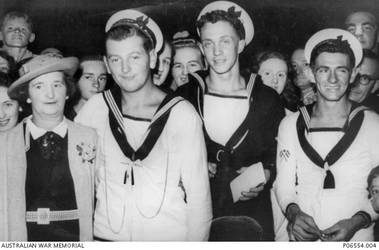 Informal portrait of Hunter Valley crew members of HMAS Sydney II, with family and friends, at Newcastle Railway Station in the evening of 12 February 1941. The ship had returned to Sydney after service in the Mediterranean, and on the 11 February the crew had enjoyed a luncheon in Sydney Town Hall following a ceremonial welcome home march through George Street, Sydney. On 19 November 1941 the Sydney was sunk in the Indian Ocean, off the coast of Western Australia, by the German auxiliary cruiser Kormoran. All 645 crew members aboard HMAS Sydney were lost. 23464 Able Seaman (AB) Martin Curtis James (front, second from left), of Newcastle, NSW, who standing next to his mother, Rose James, was 19 years of age at the time of his death. The other two crew members who were also probably on board the Sydney when it sank, are unidentified.