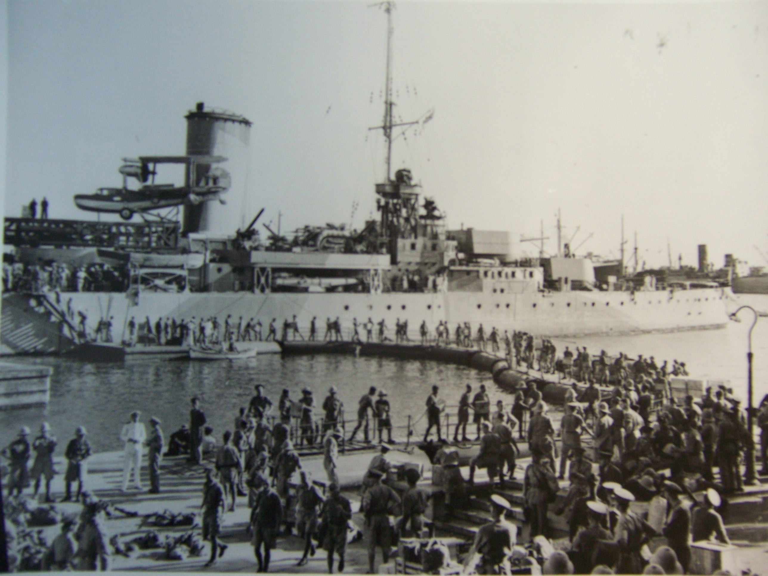 A human chain on floating platforms loads cargo onto HMAS Sydney