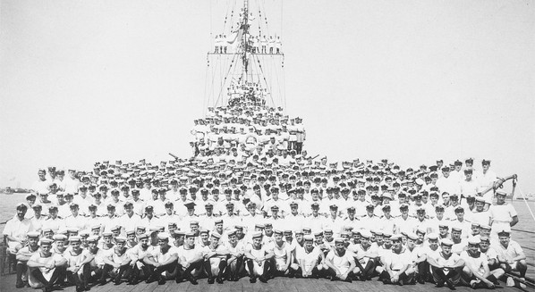 Entire crew of HMAS Sydney in full uniform posing on the deck of the ship.